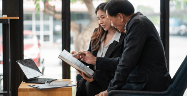 Two different aged people analysing a sheet of paper.