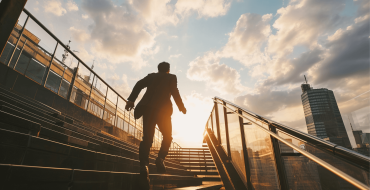Man in business dress walking up outsides stairs in the sun