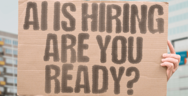 Person holding up a sign saying "AI is hiring - are you ready?"