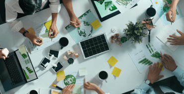 Desktop with people's arms and hands, laptops, coffee mugs