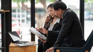 Two different aged people analysing a sheet of paper.