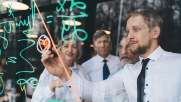 Four people on a glass whitboard