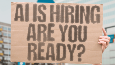 Person holding up a sign saying "AI is hiring - are you ready?"