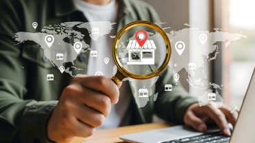 Image of man holding magnifying glass on digitaly projected map  