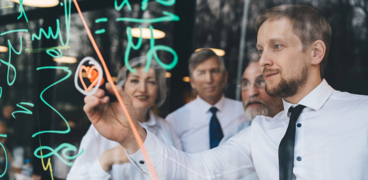 Four people on a glass whitboard