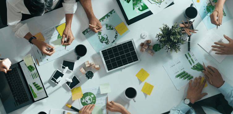 Desktop with people's arms and hands, laptops, coffee mugs 